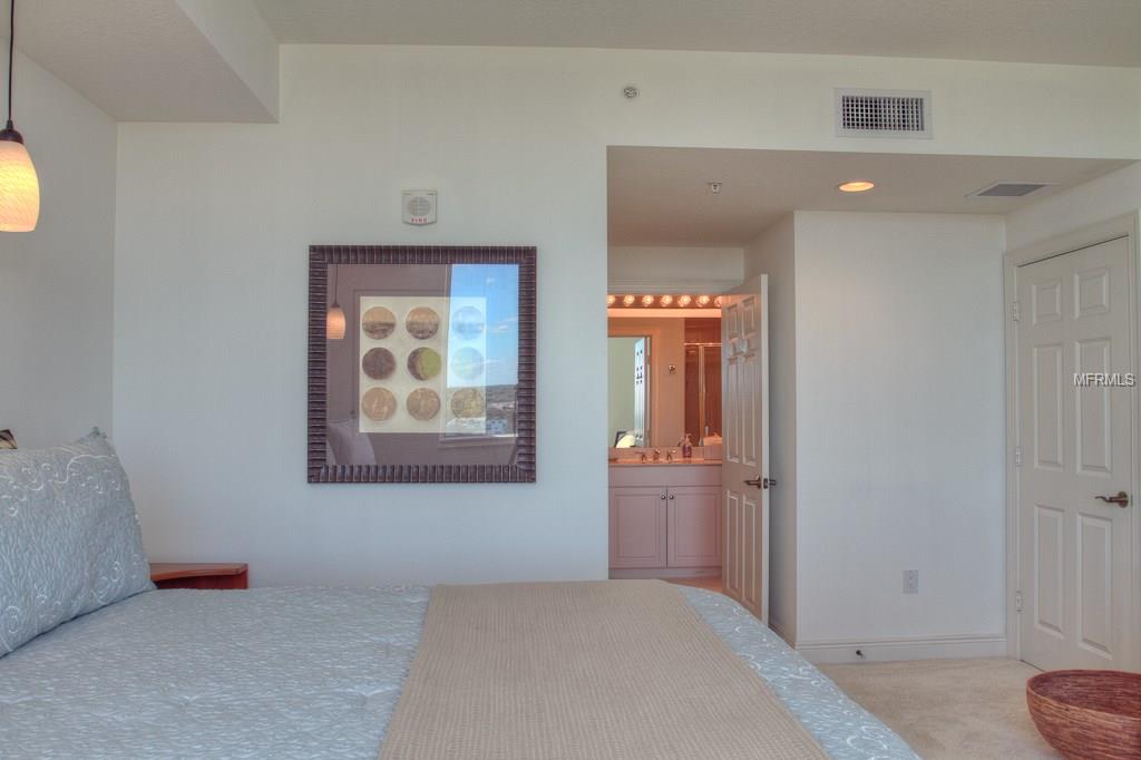 Bedroom with a bed, artwork, and bathroom door.