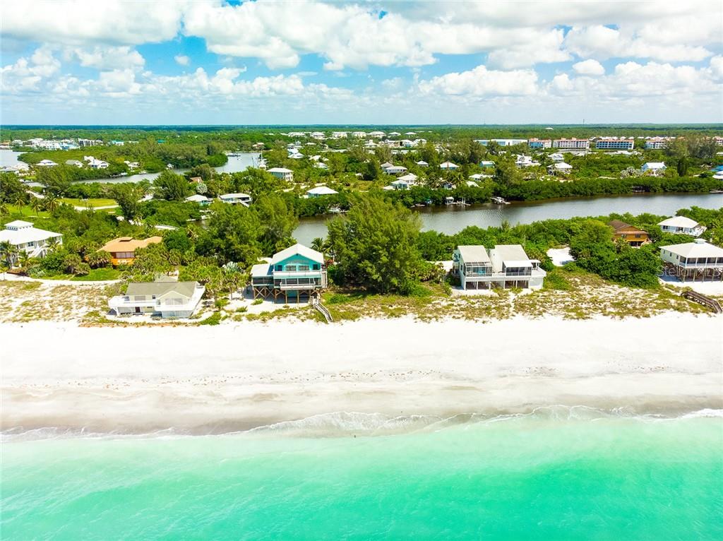 Aerial view of beach houses on a white sandy beach.