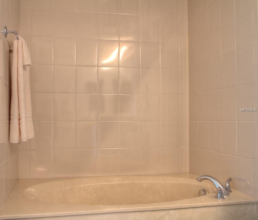 Tiled bathroom with a bathtub and towel.