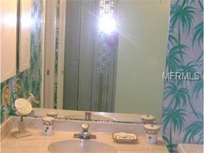 A bathroom sink with palm tree wallpaper.