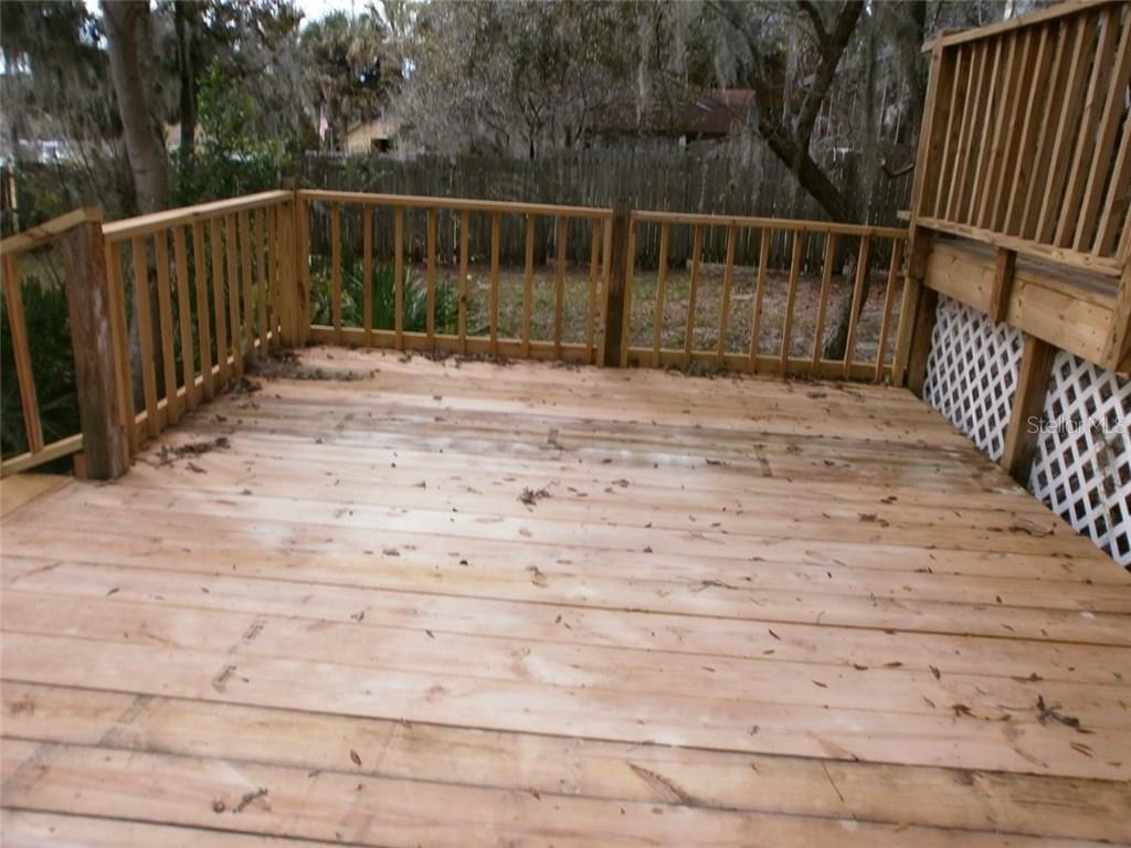 Wooden deck with railing and foliage.