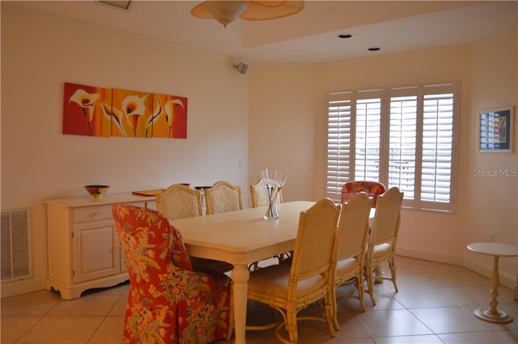 White dining room with floral art and shuttered window.