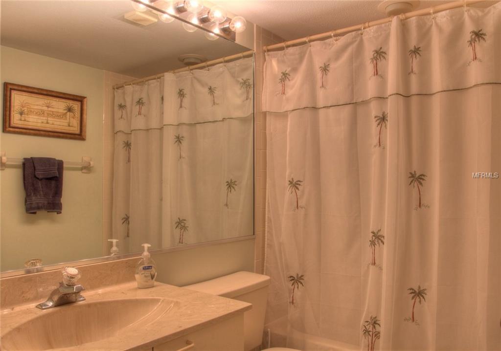 A white bathroom with a palm tree shower curtain.