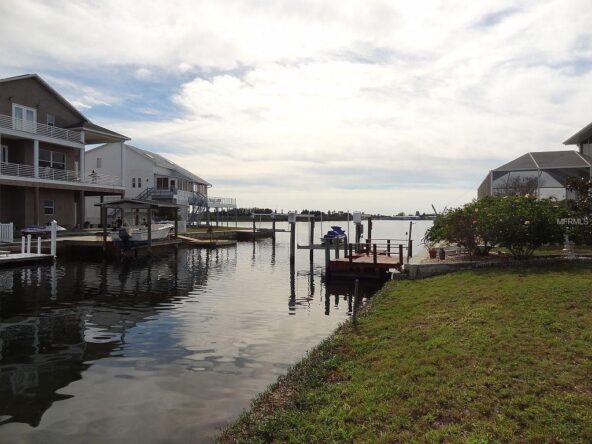 Waterfront homes with boat dock and green grass.