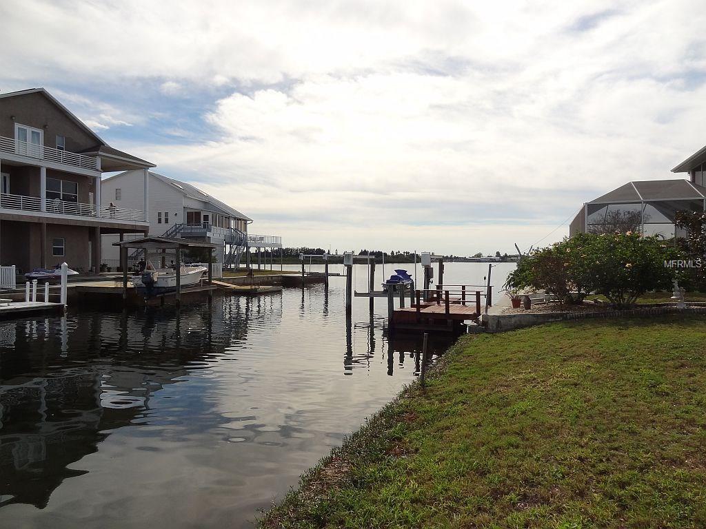 Waterfront homes with boat dock and lush grass.