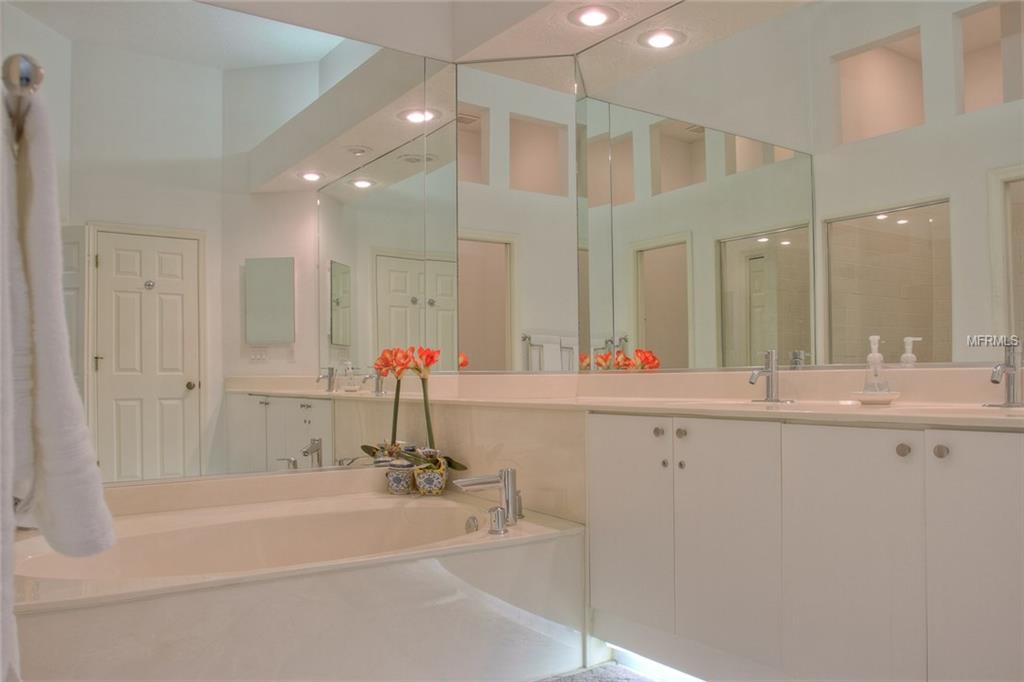 White bathroom with a bathtub and double sinks.