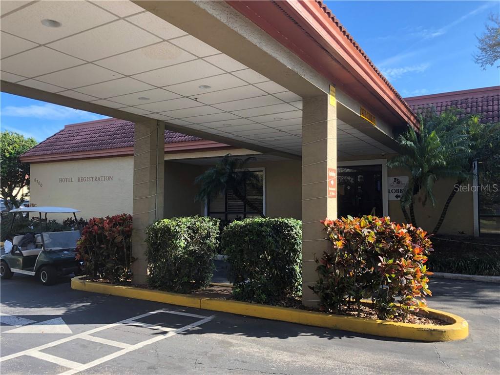 Hotel entrance with golf cart and shrubs.