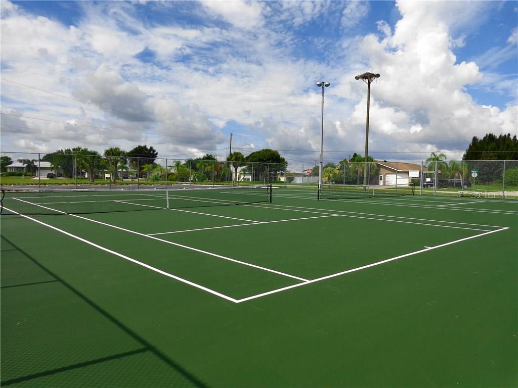 Green tennis court with white lines.