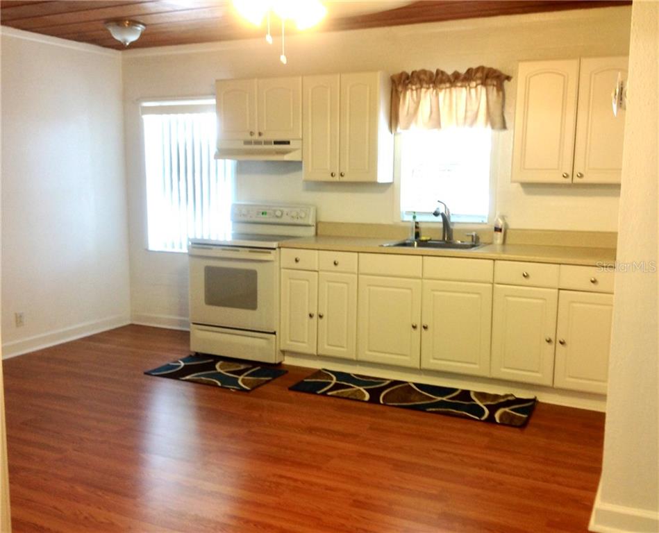 White kitchen with wood floors and rugs.