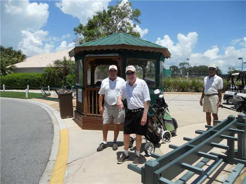 Three men in golf attire stand by a golf cart.