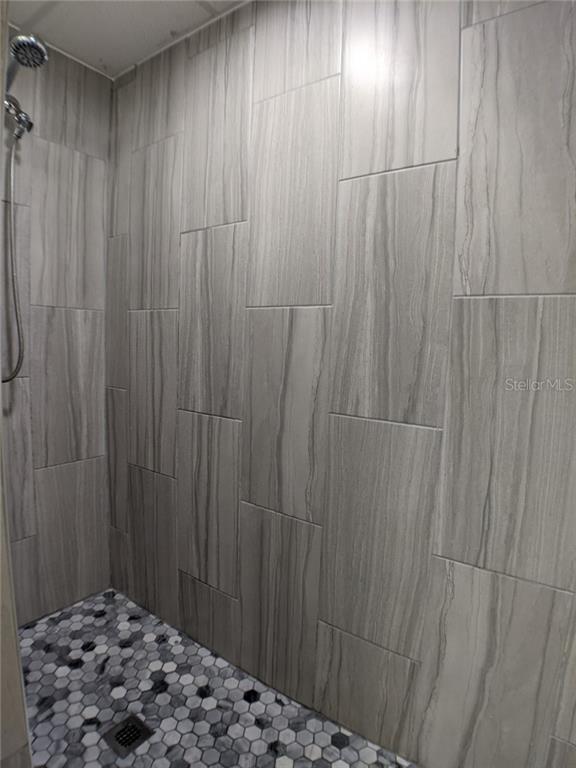 Shower stall with gray tile walls and floor.