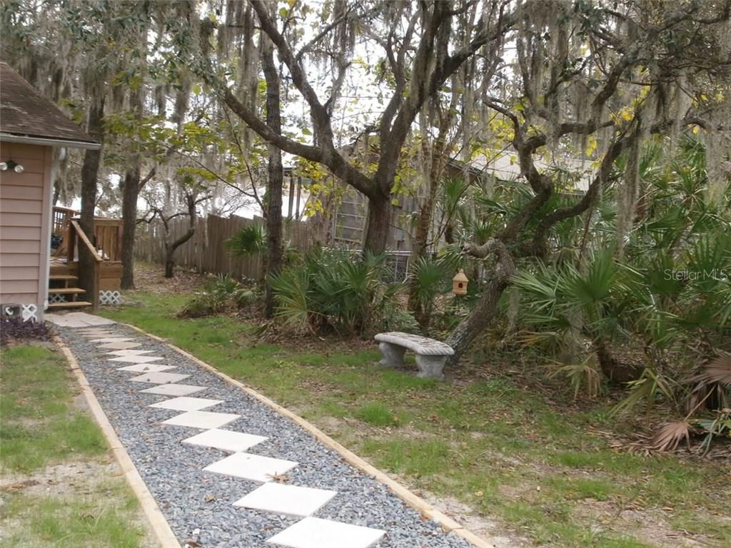 Stone pathway leading to a bench in a garden.