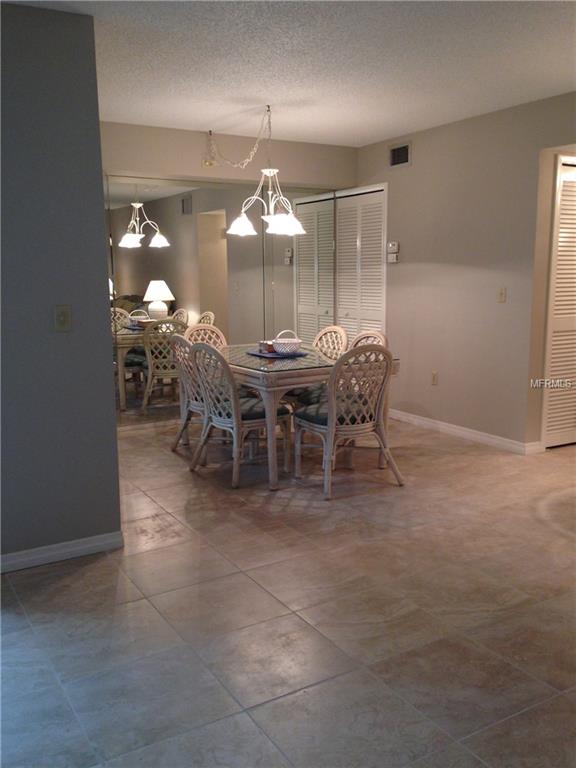 Dining room with tiled floor and white chairs.