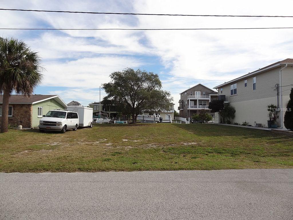 Empty lot with van and houses in background.