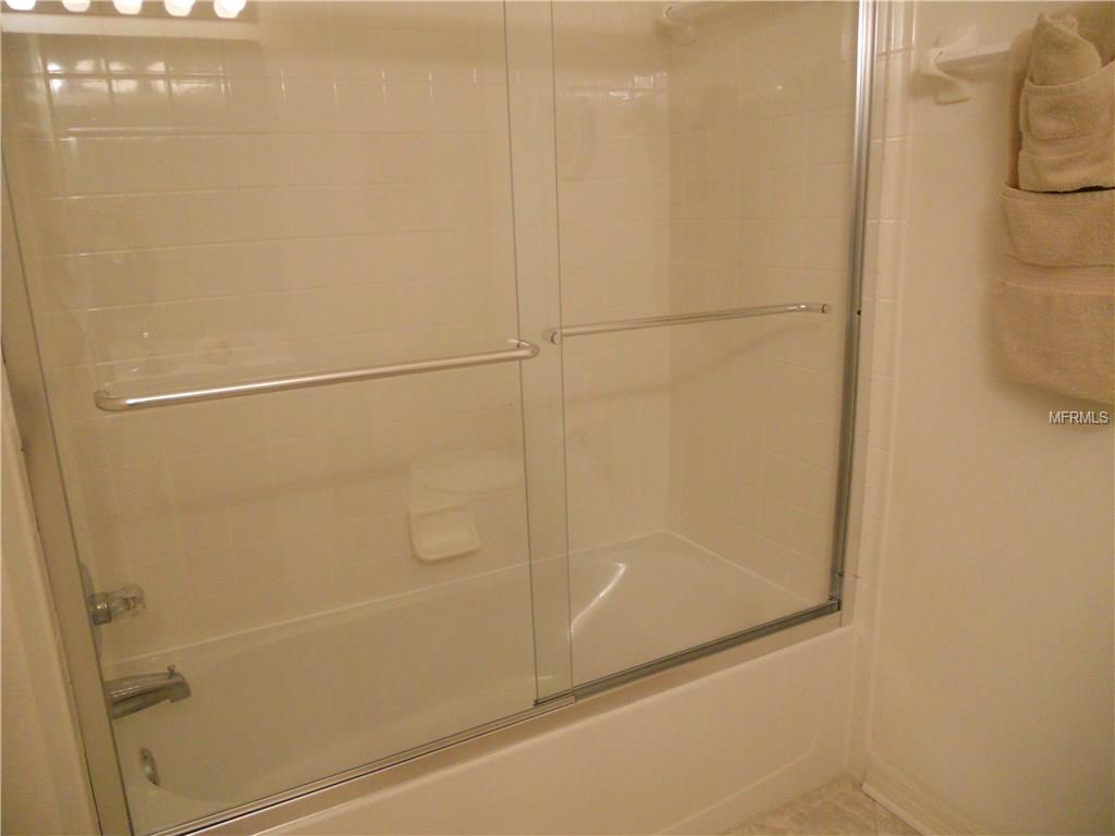 White tiled shower with glass door.