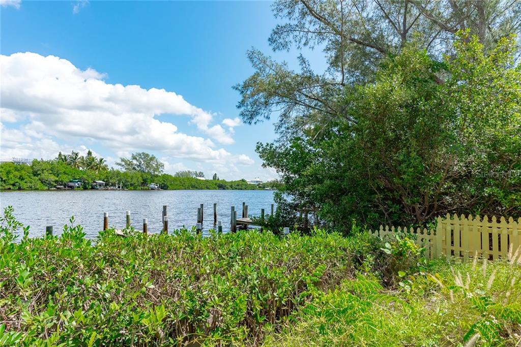 Waterfront view with trees and a fence.