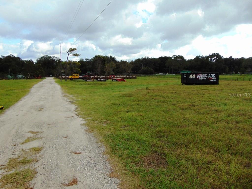 Dirt road leading to a grassy field.