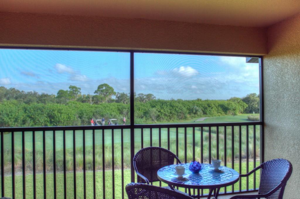 Patio overlooking a golf course with chairs and a table.