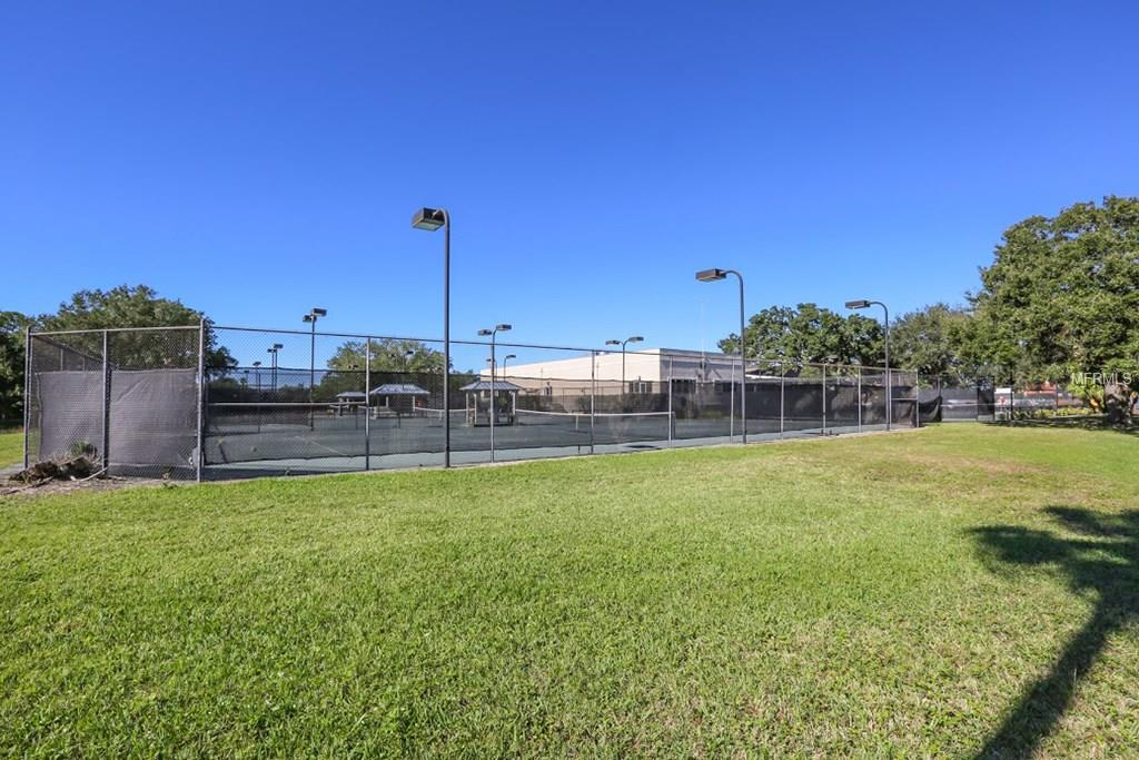 Tennis court with green grass and lights.