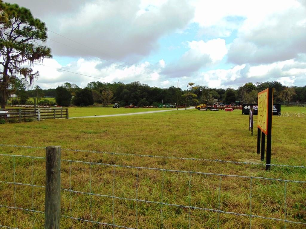 Green grassy field with a fence and signs.