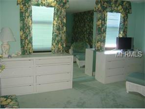 A bedroom with white furniture and green carpet.