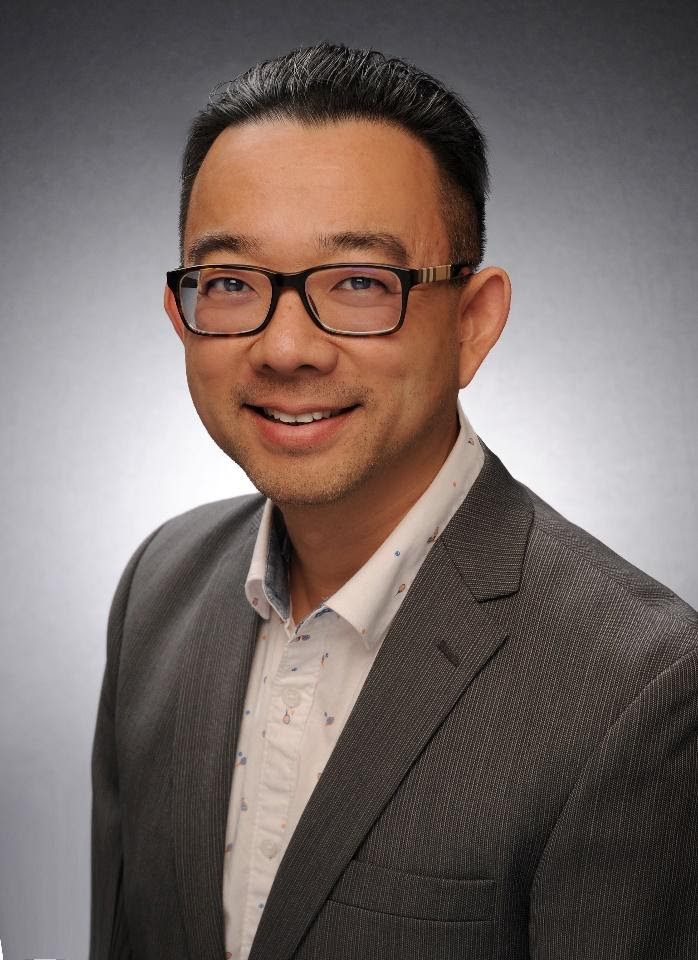 Man in suit and glasses smiling.