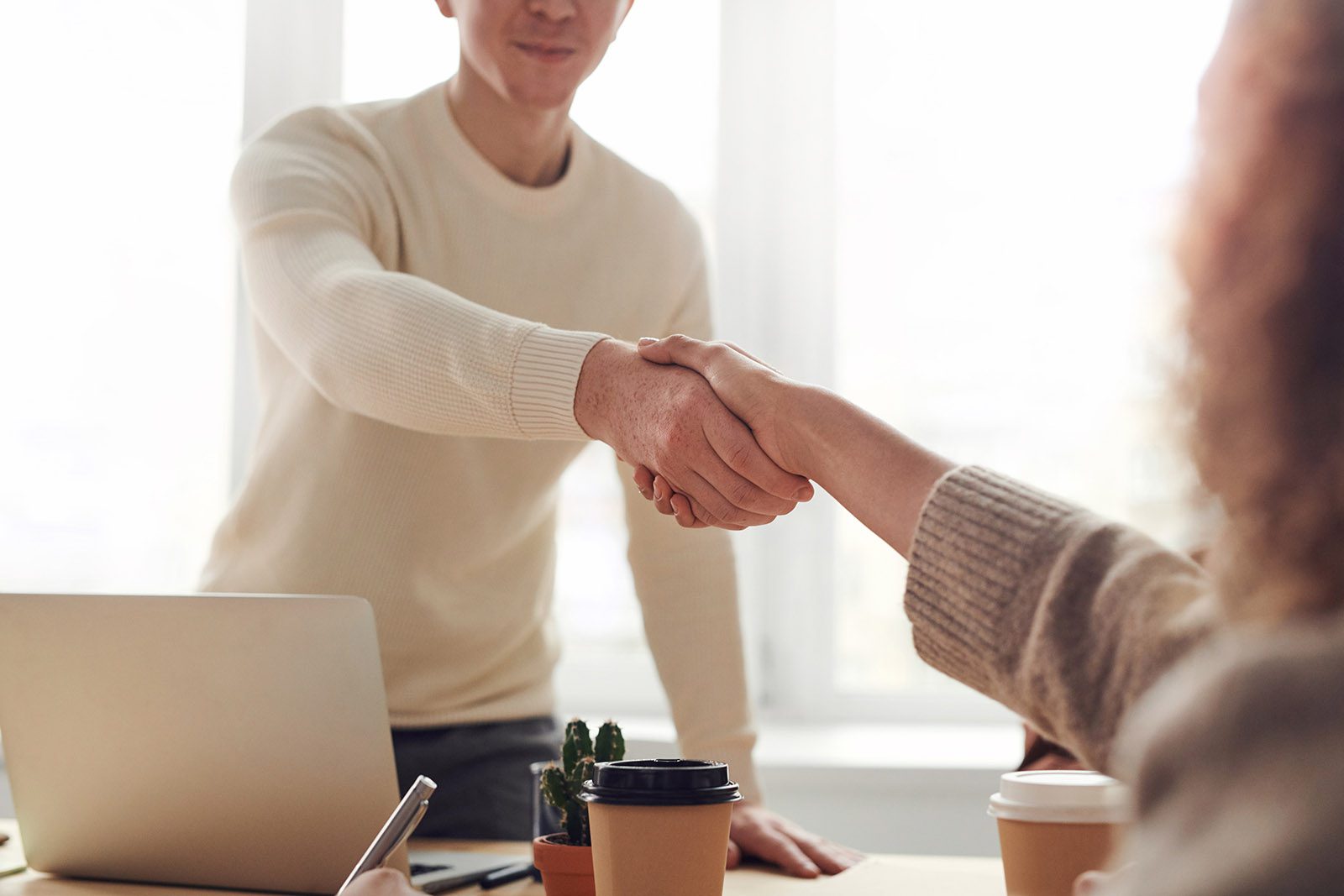 Two people shaking hands in an office.