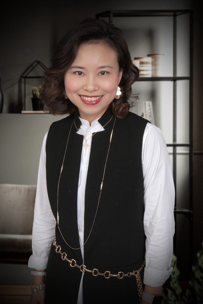 Smiling woman in black vest and gold chain.