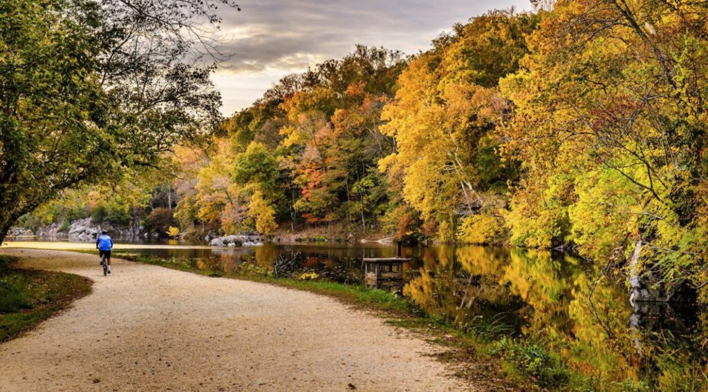 A man bikes on a path by a lake.