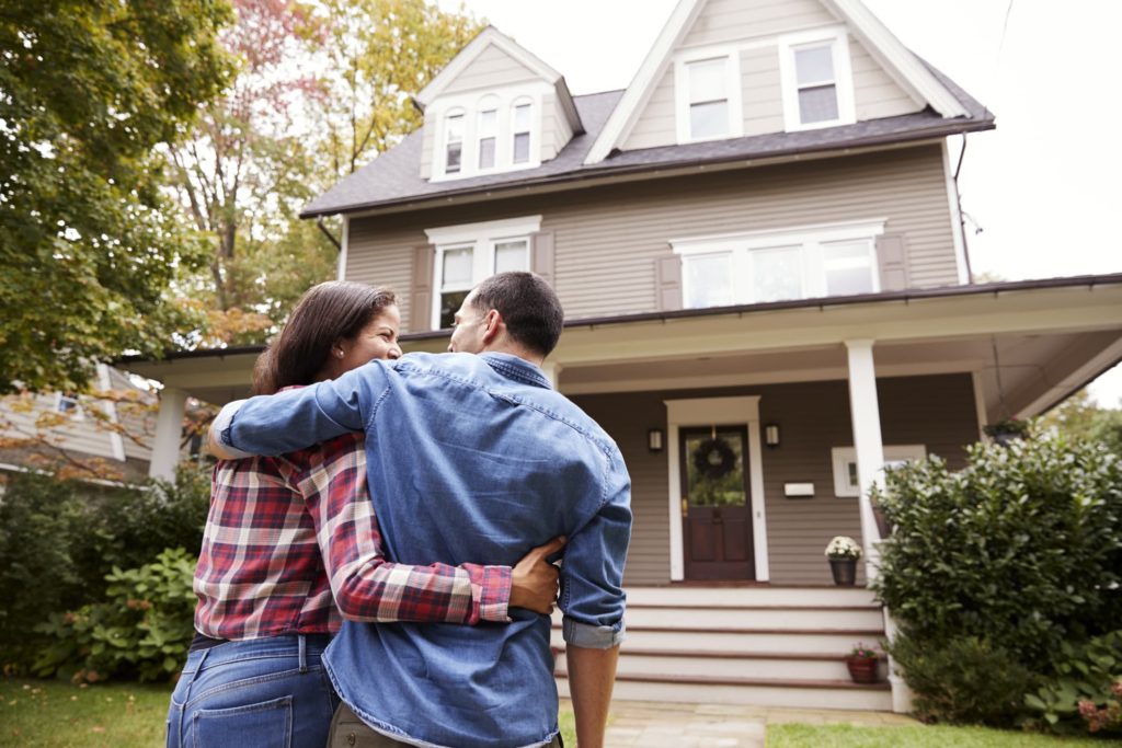 Couple embracing in front of house