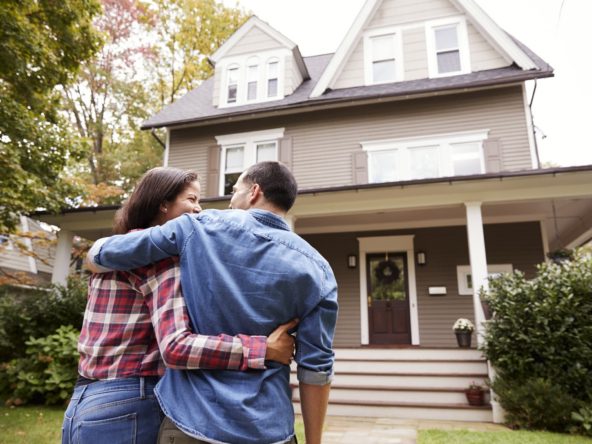 Couple embracing in front of house
