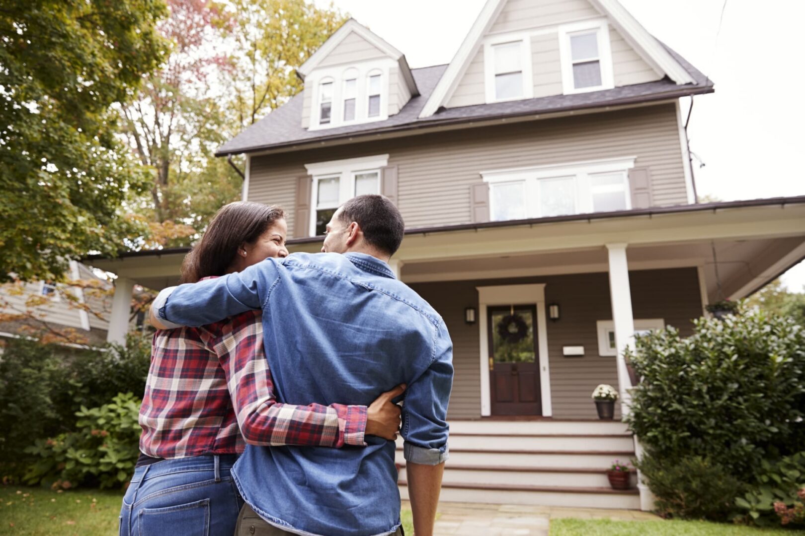 Couple embracing in front of house