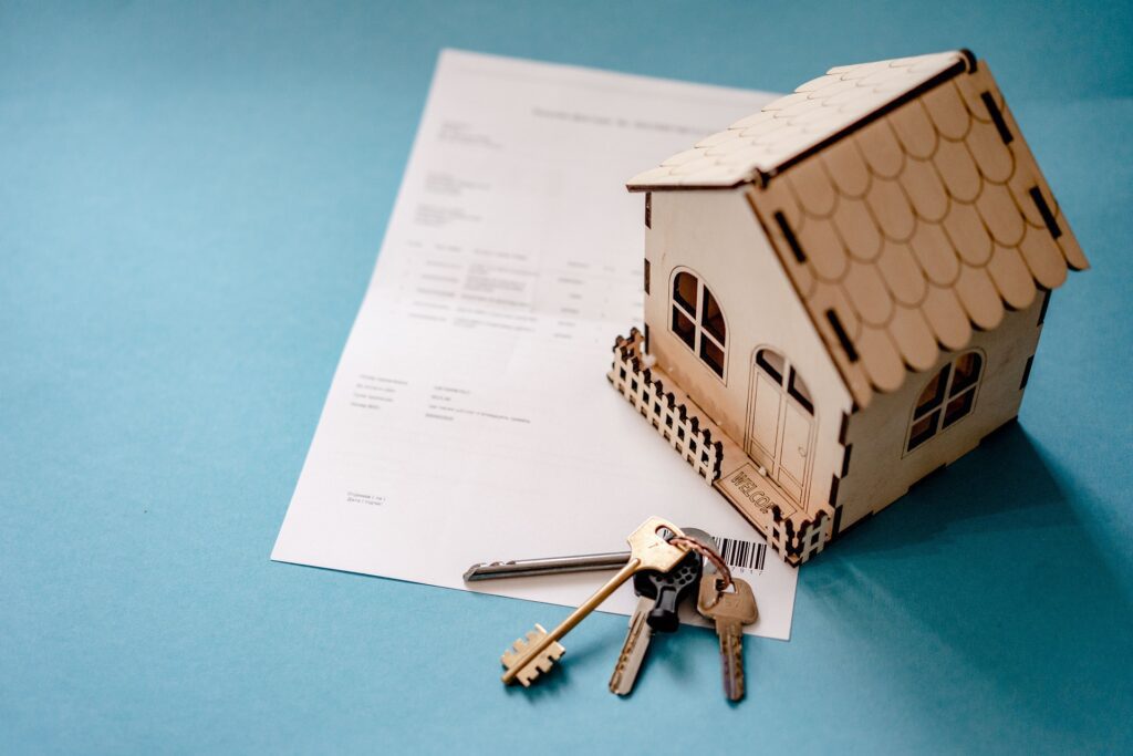 Wooden house model, keys, and a document.