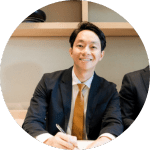 Smiling man in suit signing a document.