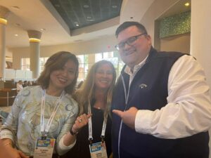 Three people smiling for a photo at a conference.