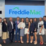 Group of people in front of Freddie Mac logo.