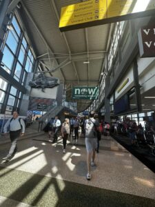 Crowded airport terminal with signs and people.