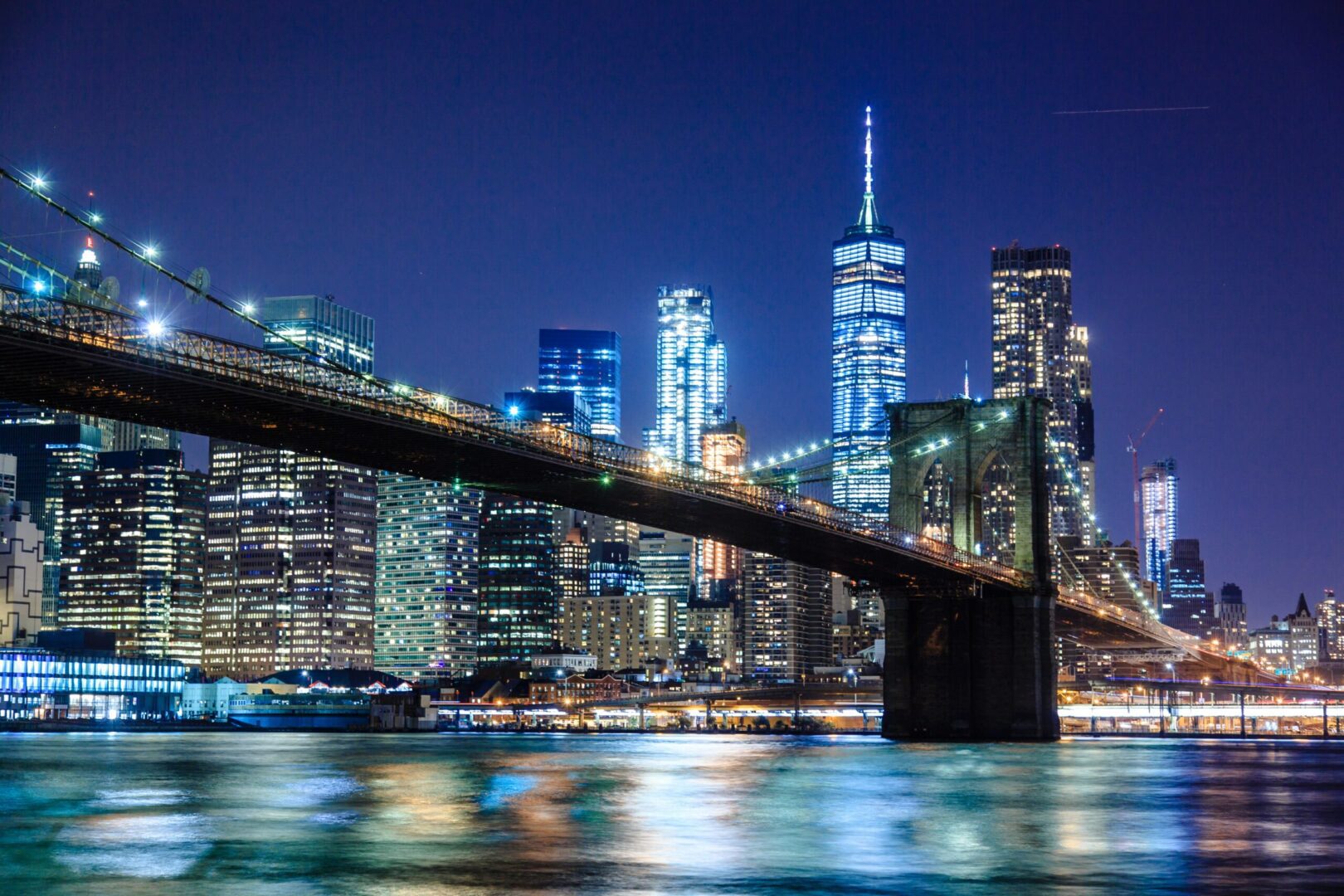 Brooklyn Bridge at night with cityscape.