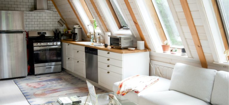 Modern white kitchen with skylights and couch.